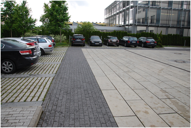 Parkovací stání u kancelářských budov řešené dlažbou s otevřenými spárami